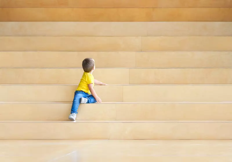 Liten gutt sitter i en trapp. Foto