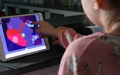 Et barn tester ut appen ZuperSmart på et nettbrett.